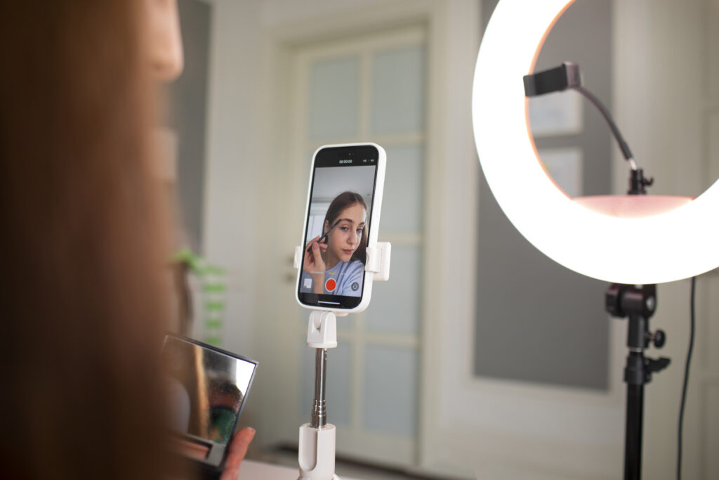 Influenciadora se gravando enquanto faz maquiagem.
